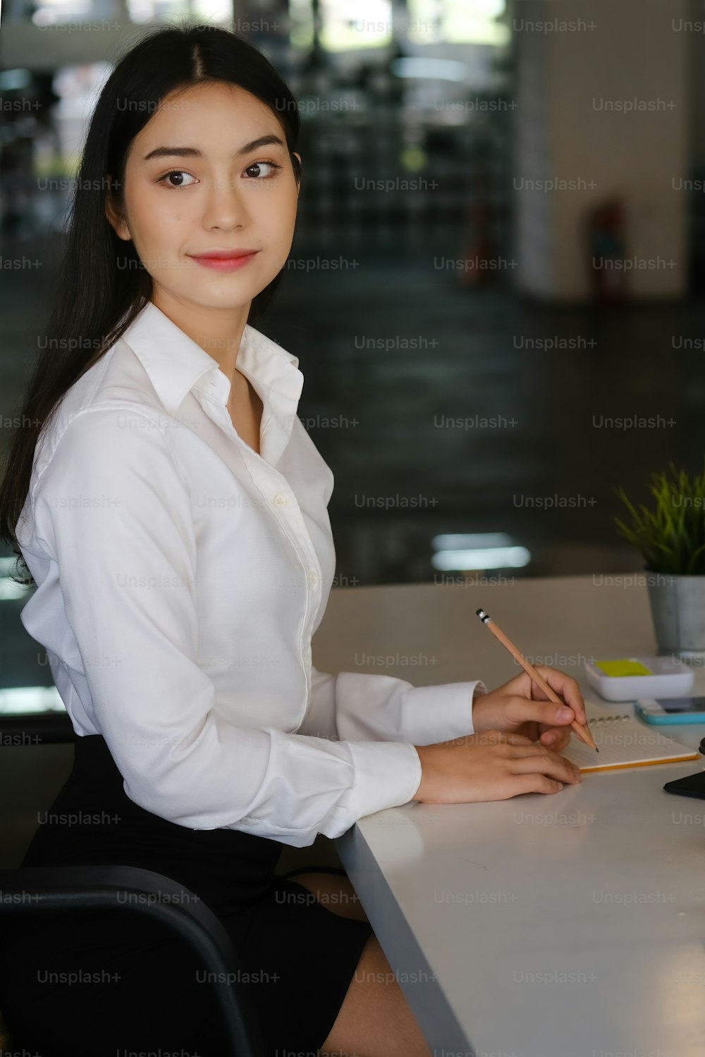 Attractive female office worker sitting at her workplace an looking away.