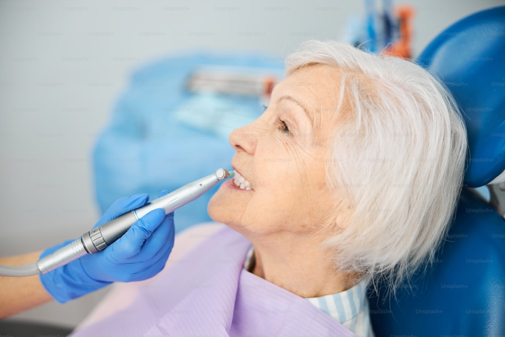 Dental procedure of removing plaque and tooth decay from elderly citizen teeth with prophy cup on handpiece