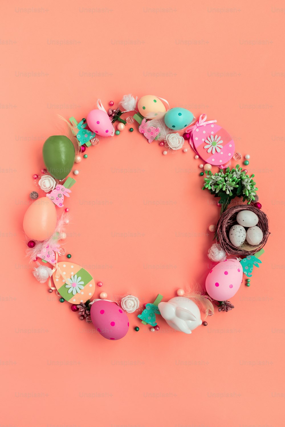 Circle wreath shape made of colorful spring flowers and eggs on pink background.  Easter celebration concept. Top view. Flat lay