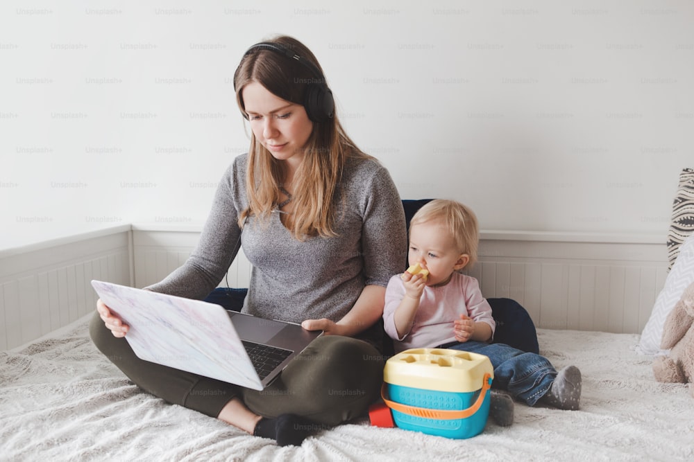 Caucasian mother with baby working online from home on Internet. Workplace of freelancer woman with kid. Coronavirus self-isolation social distance on quarantine. Stay home single mom.