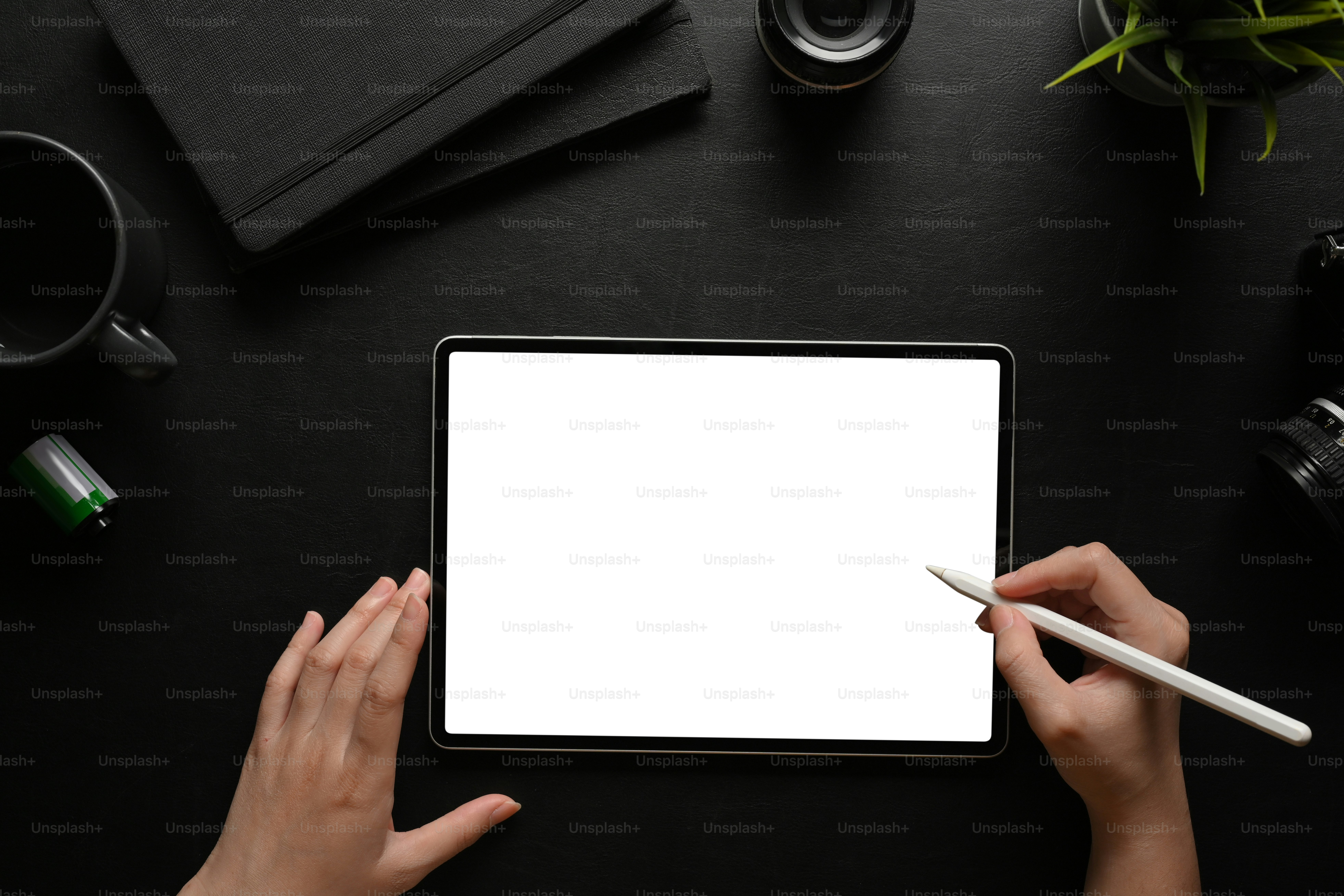 Top view of female hands using digital tablet with stylus pen on dark workspace, clipping path