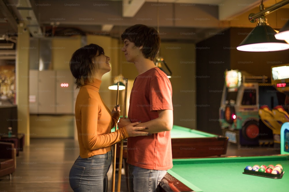 Couple in the billiard room talking.
