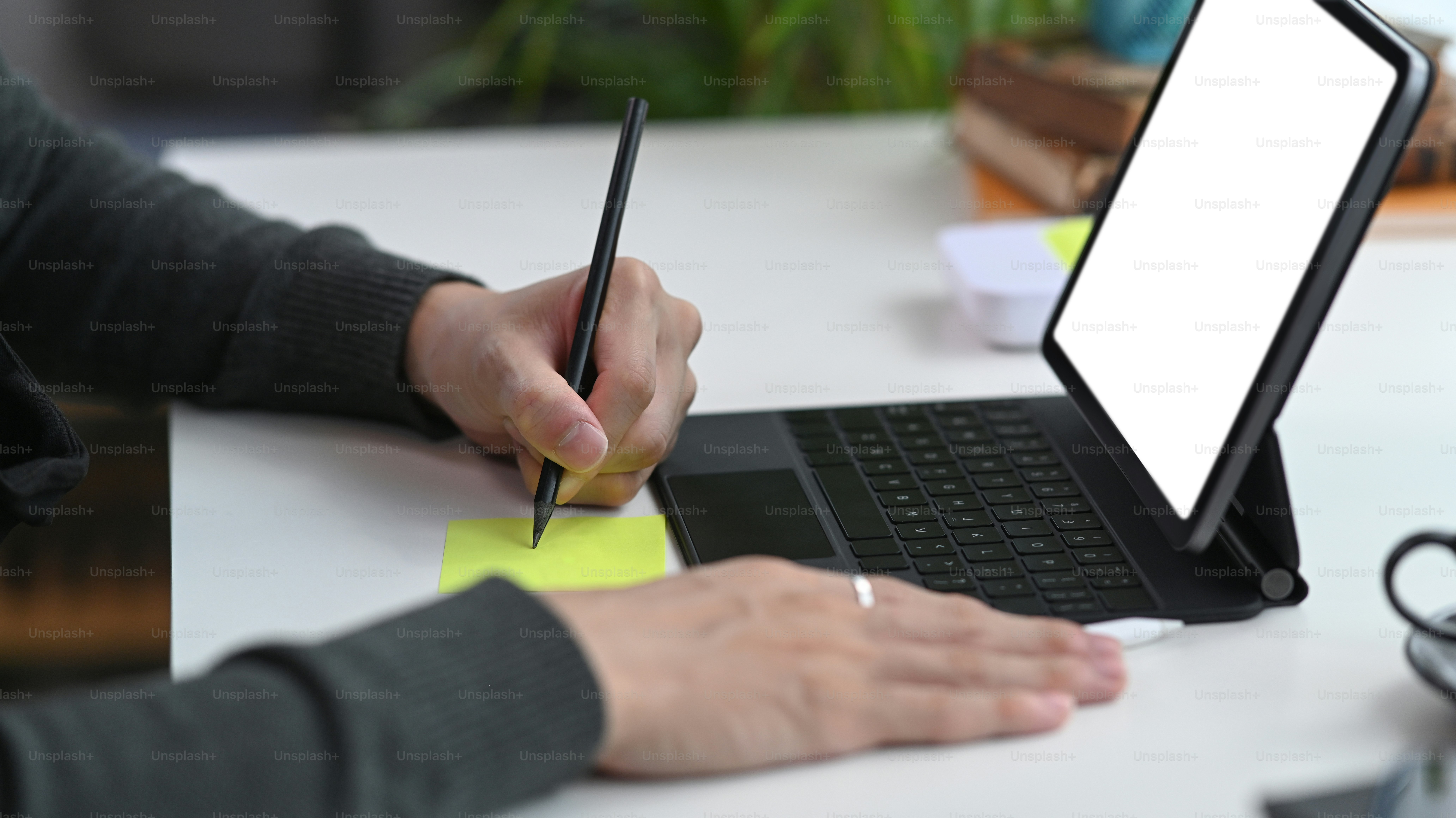 Close up view of man making note on sticky note and working with computer tablet.