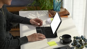Young man designer holding stylus pen and working with computer tablet at workplace.