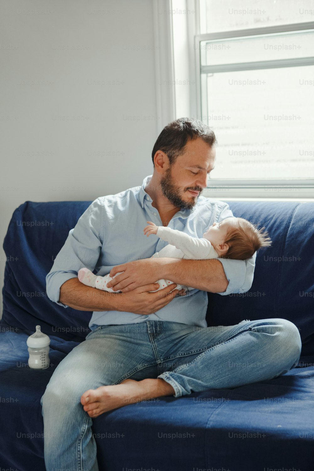 Orgoglioso padre caucasico con neonato. Genitore che tiene a dondolo il figlio della figlia del figlio sulle mani. Stile di vita autentico, momento di genitorialità felice, paternità. Vita familiare da papà single. Festa del papà.