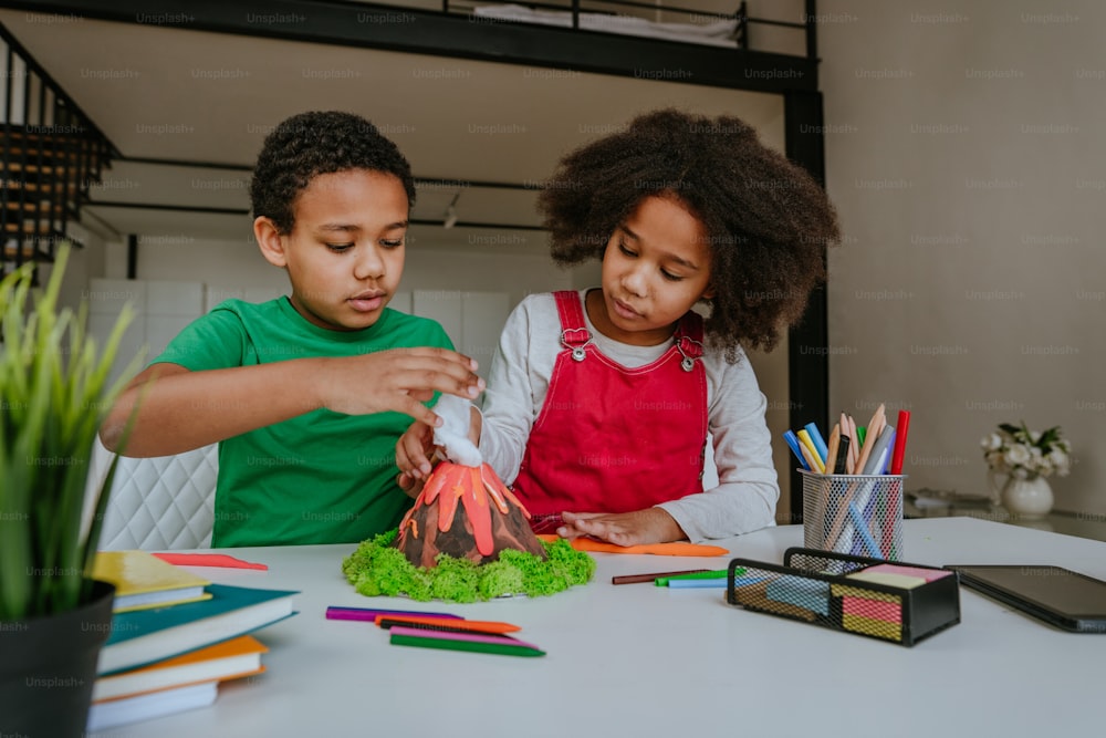 La sœur et le frère s’amusent à fabriquer un modèle de volcan bricolage à partir d’enfants qui jouent à l’argile pour le projet scolaire. Concept d’éducation à domicile.