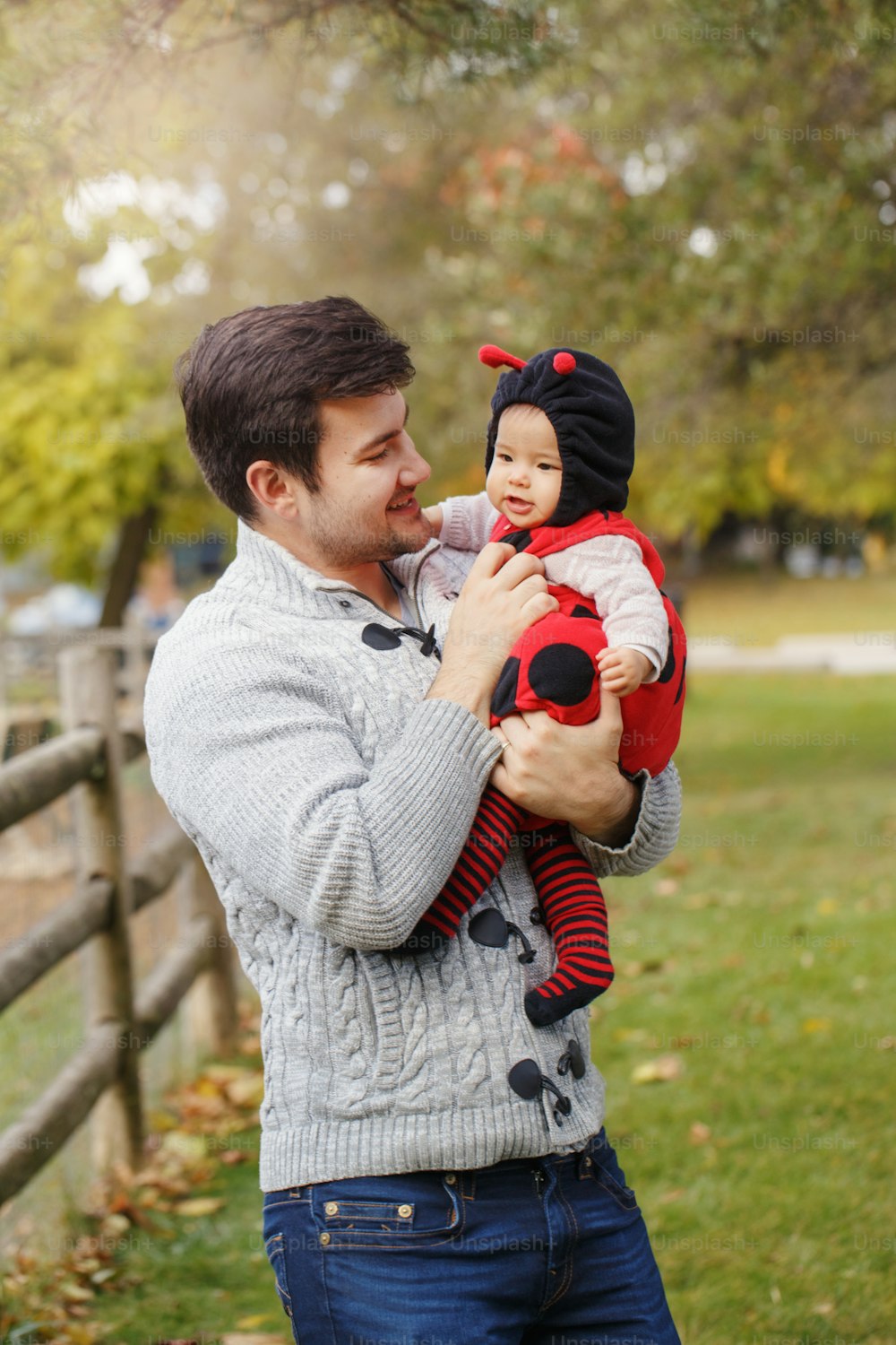 Happy smiling Caucasian father dad with cute adorable baby girl in ladybug costume. Family in autumn fall park outdoor. Halloween seasonal holiday concept. Fathers Day.