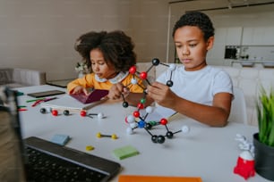 Niño y niña haciendo modelos moleculares aprendiendo ciencia química en casa.