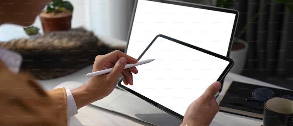 Vista de cerca del hombre de negocios sosteniendo el lápiz óptico apuntando en la pantalla en blanco de la tableta digital.