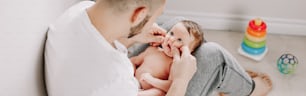 Father holding newborn baby on laps. Man parent playing with child daughter son. Authentic lifestyle candid moment. Proud young dad. Family fathers day. Web banner header for website.
