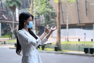 Femme d’affaires en masque de protection appliquant de l’alcool désinfectant en spray sur la main pour prévenir le virus et les bactéries.