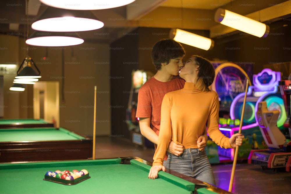 Couple in the billiard room. Couple is kissing.