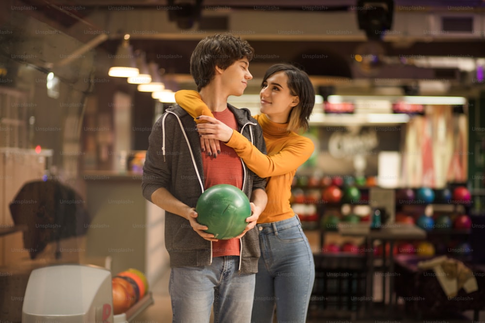 Young couple having fun in bowling alley. Happy girl hugging her boyfriends.
