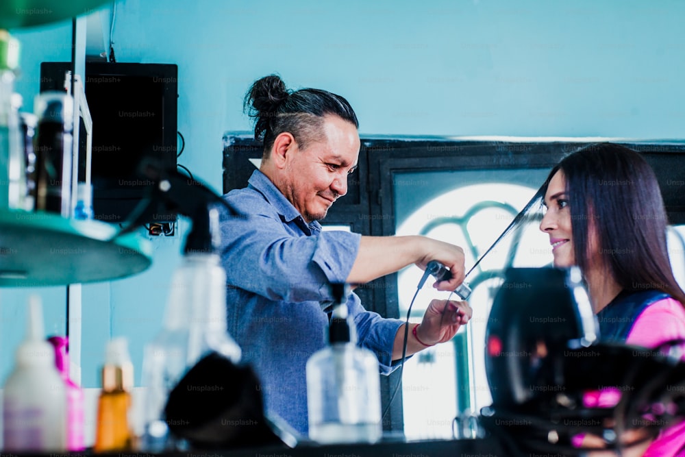 homem latino trabalhando como cabeleireiro e cortando o cabelo de uma cliente do sexo feminino em um salão de beleza pequena empresa na cidade do México