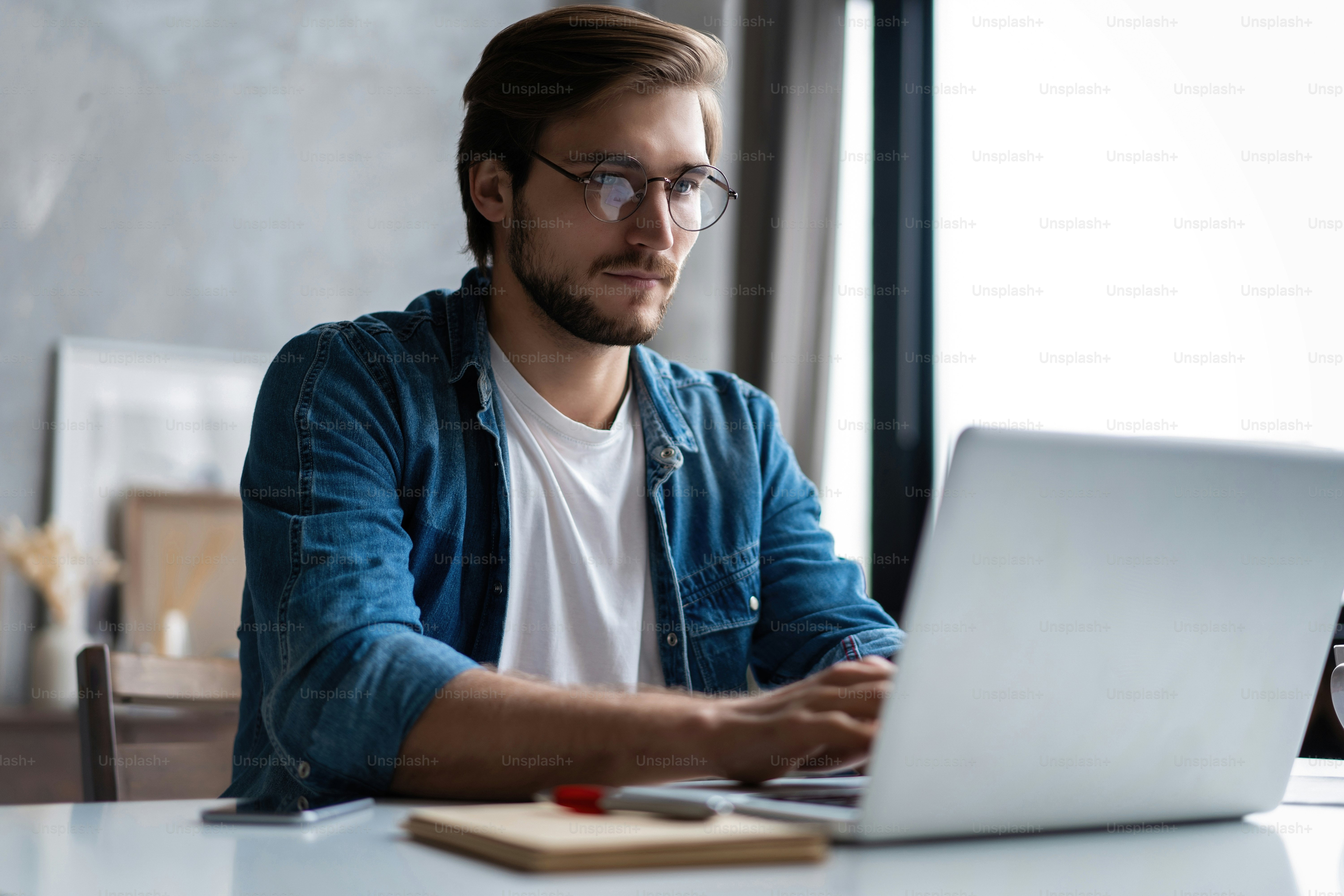 Smiling young man freelancer using laptop studying online working from home, happy casual guy typing on pc notebook surfing internet looking at screen enjoying distant job sit at table