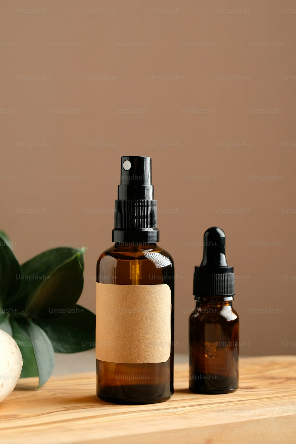 Set of natural organic SPA beauty products on wooden board. Amber glass spray bottle, homemade soap, serum, and green leaf. Bio cosmetics branding, packaging design.