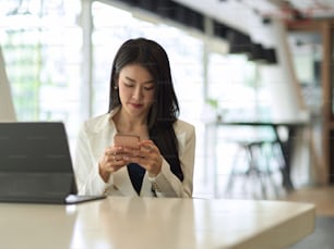 Ritratto di donna d'affari che lavora con smartphone e tablet digitale in una moderna stanza d'ufficio