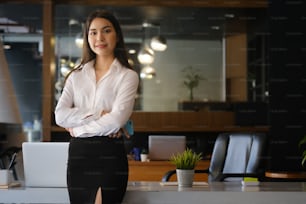 Charming businesswoman standing with arms crossed and looking at camera.