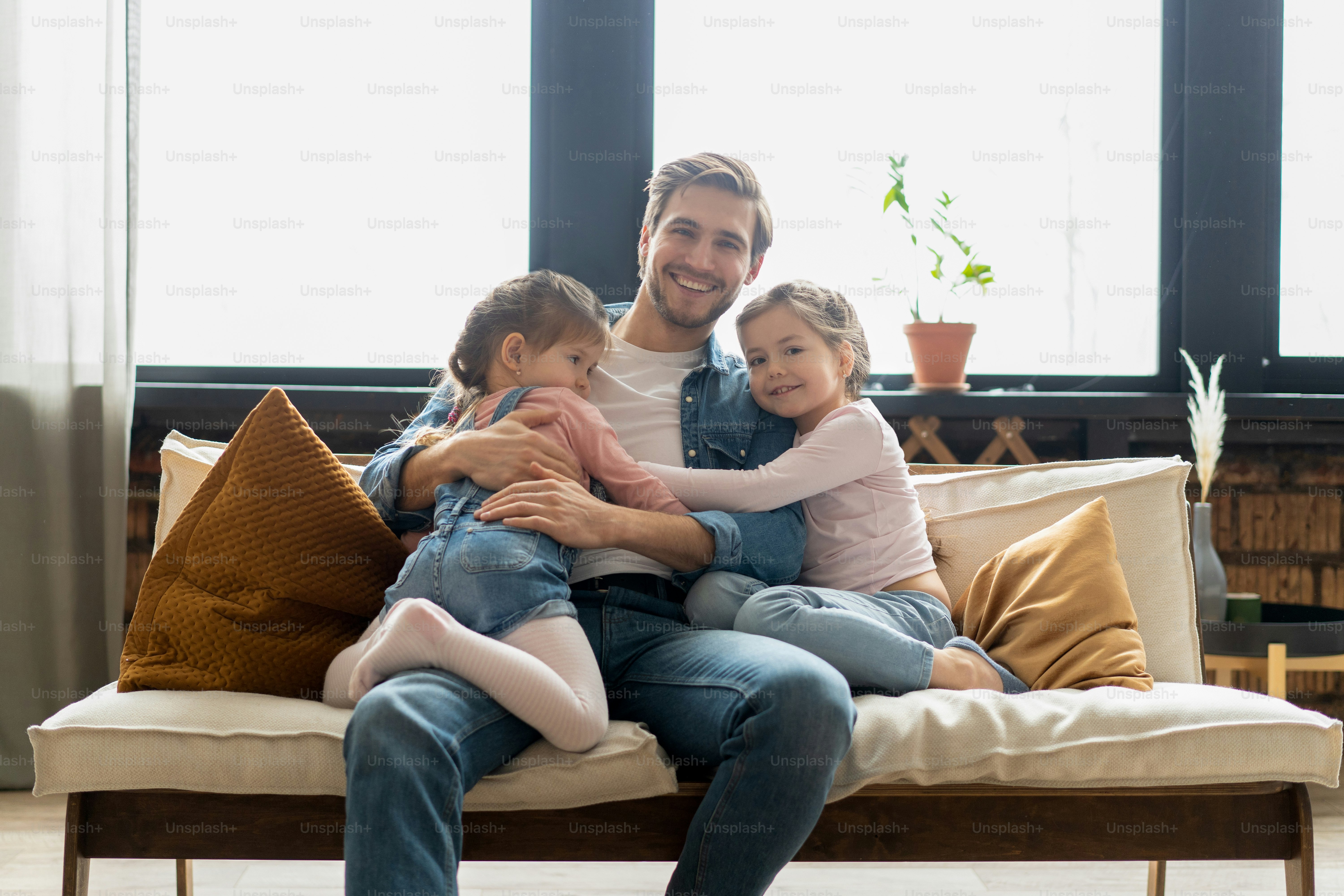 Portrait of handsome father and his cute daughters hugging and smiling
