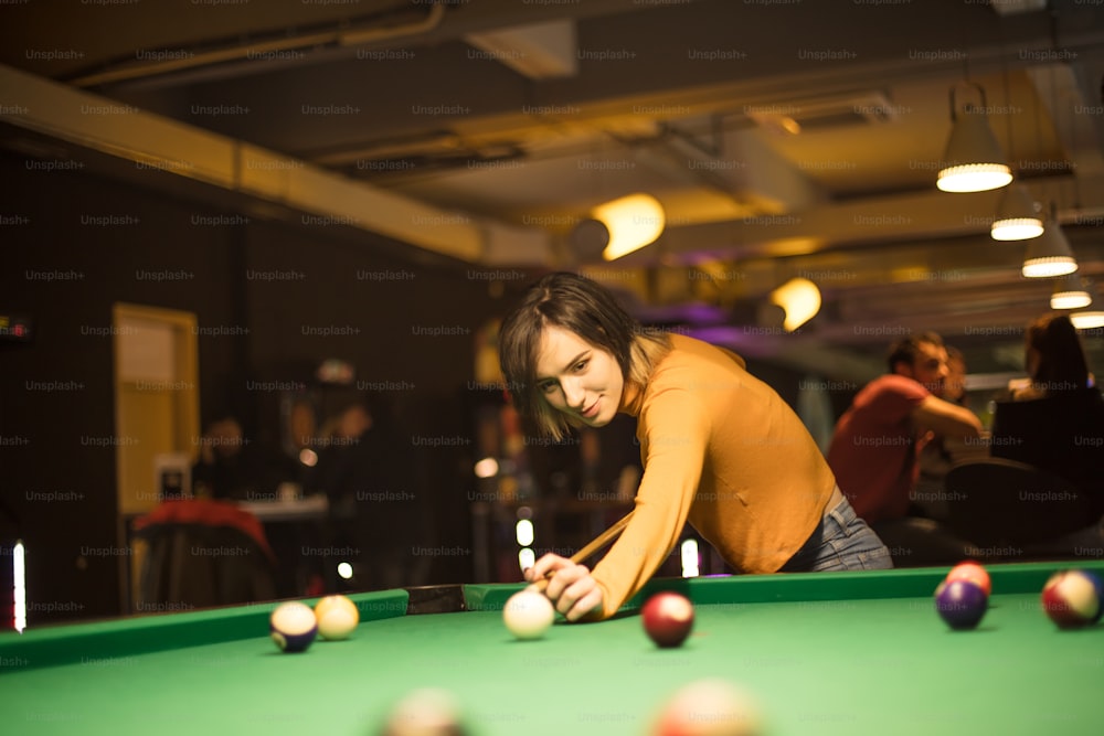 Young Woman playing billiard alone. Focus is on woman.