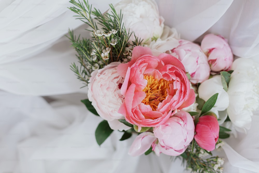 Bellissimo elegante bouquet di peonie su morbido tessuto bianco. Fiori di peonia rosa e bianchi su tulle su sedia rustica in legno. Buona festa della mamma. Mattina nuziale. Spazio per il testo