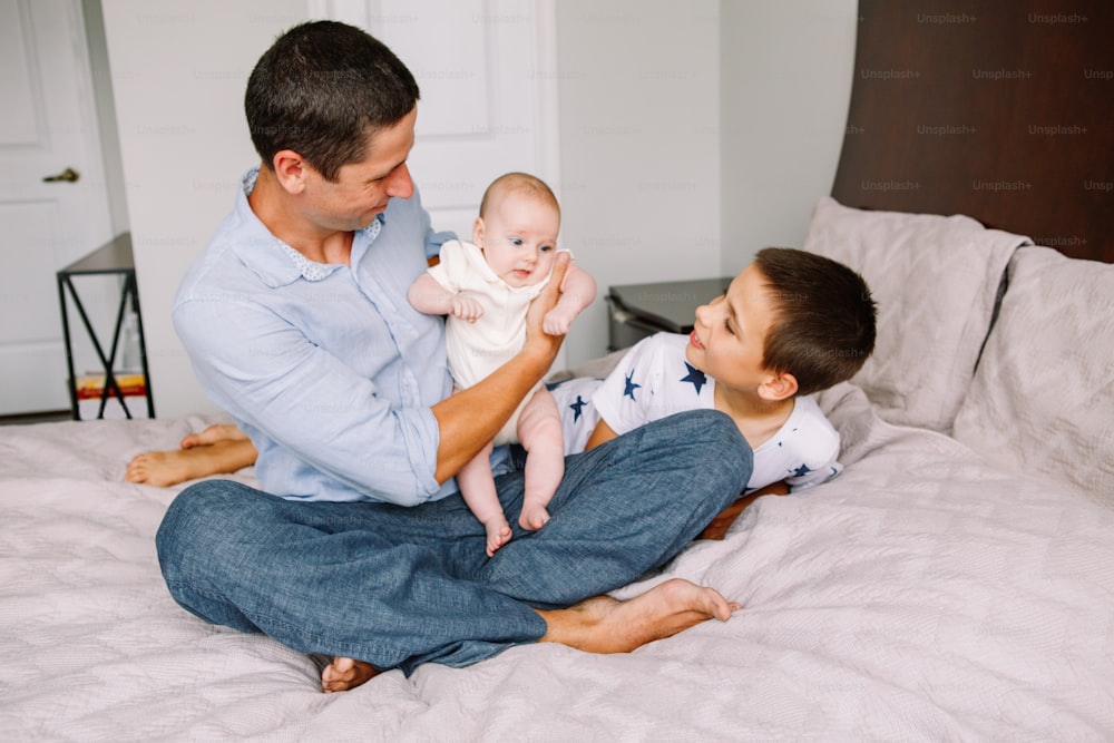 Fathers Day holiday. Caucasian father dad holding newborn baby. Brother playing with sister. Siblings relationship. Man parent spending time with children kids. Authentic lifestyle family moment.