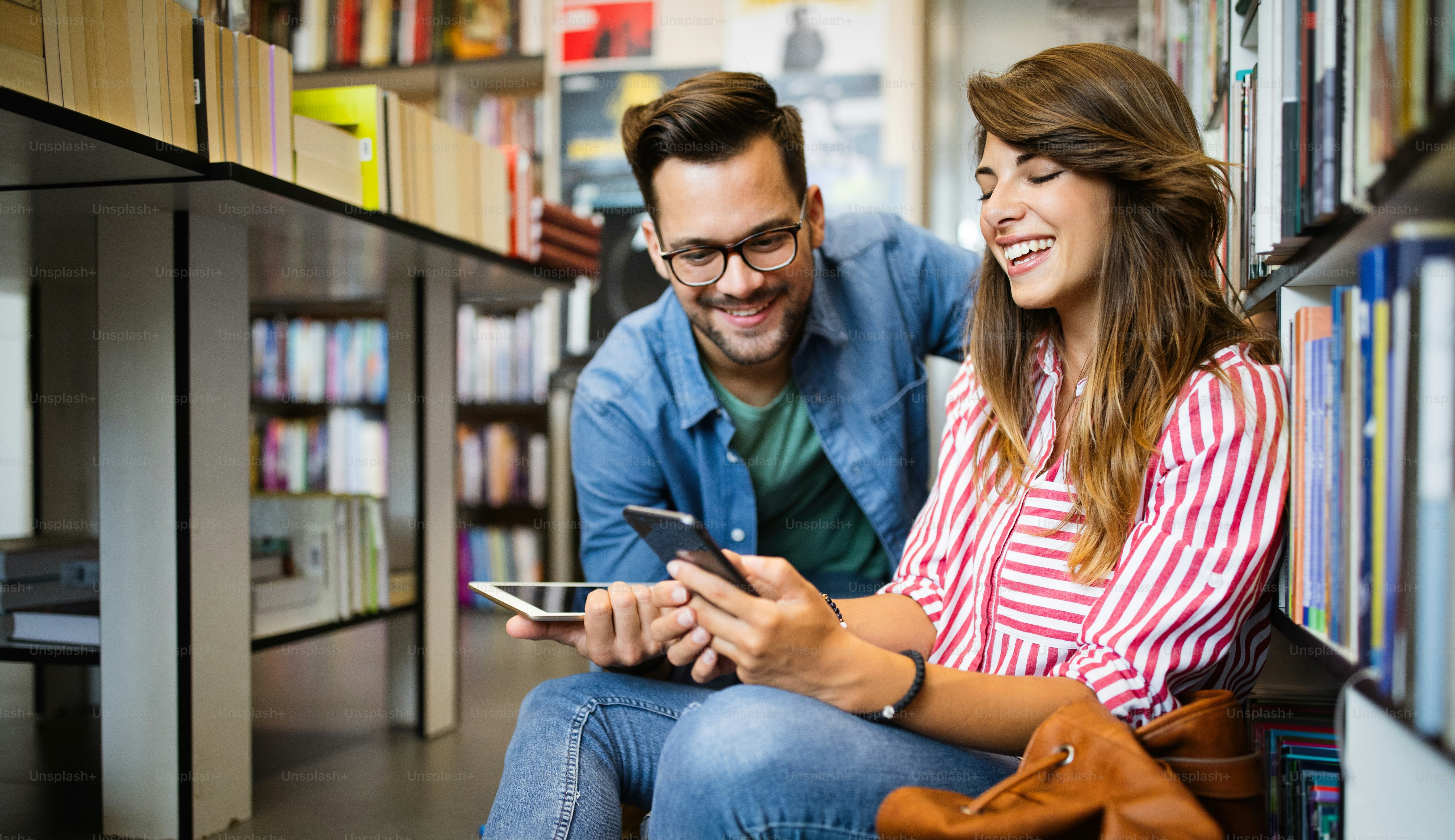 Happy beautiful friends taking a selfie in school library.