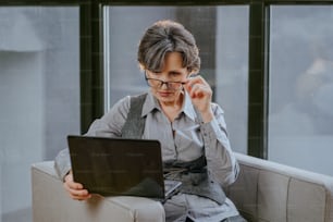 Ritratto di donna d'affari matura che utilizza il laptop per il coaching online o la consultazione seduta su una poltrona in ufficio.