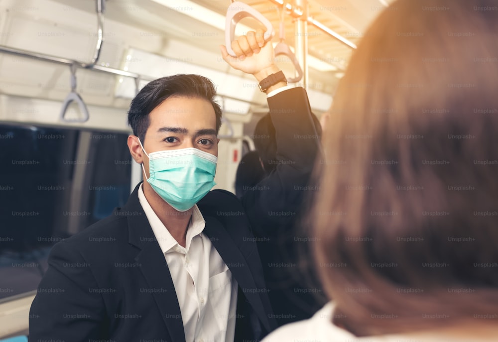 電車に乗っている人は、抗ウイルスマスクを着用し、ラッシュアワーに旅行します。スカイトレイン内の乗客は、全員の顔にマスクを着けています。