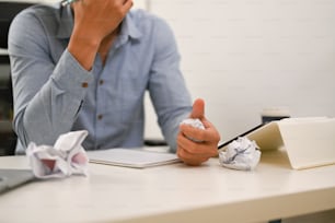 Frustrated businessman crumpled paper balls at his office desk.