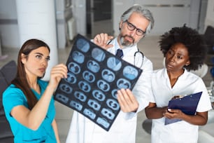 Closeup portrait of intellectual doctors healthcare personnel with white labcoat, looking at lungs x-ray radiographic image, ct scan, mri, isolated hospital clinic background. Radiology department