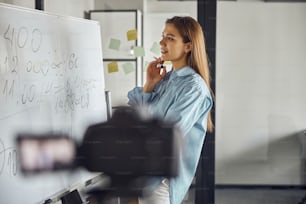 Side view of a young woman with a marker pen in her hand staring at the whiteboard