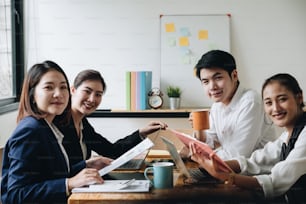 Ritratto di un giovane team di imprenditori asiatici che lavorano insieme in una moderna startup di uffici open space. Guardando la macchina fotografica.