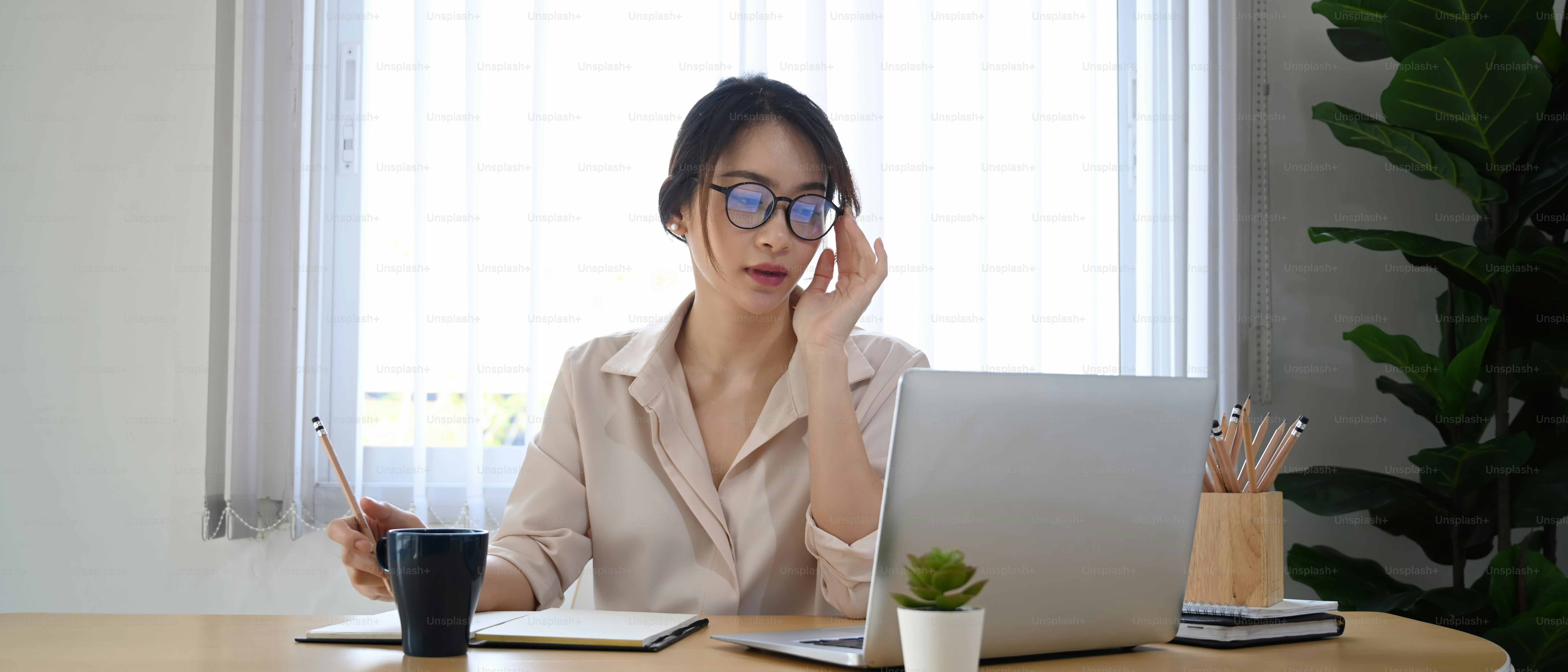 Joven mujer de negocios en anteojos trabajando en computadora portátil en la oficina.