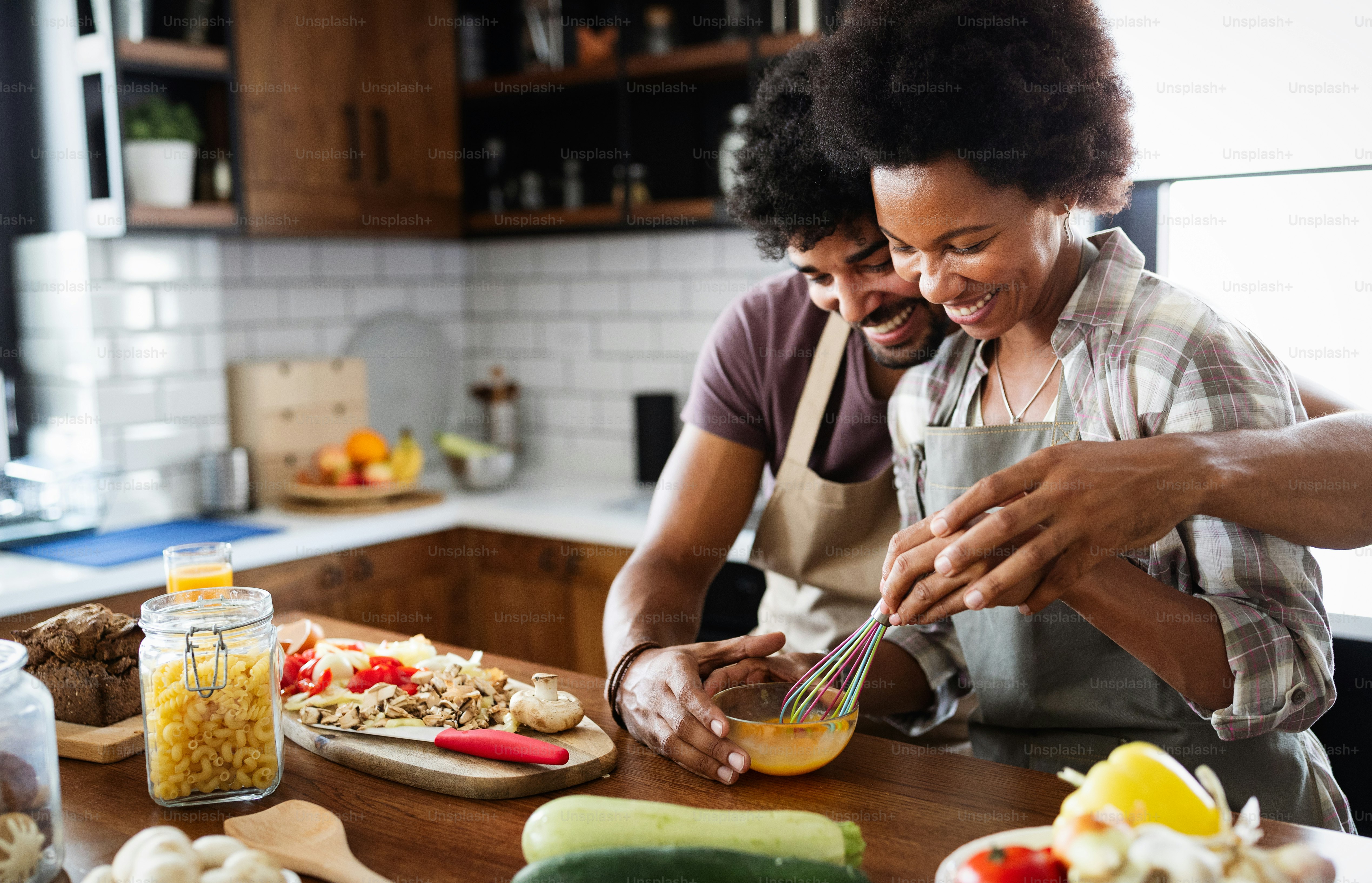 Beautiful young couple having fun and laughing while cooking in kitchen at home