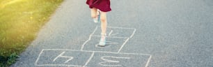 Kind Mädchen Beine spielen Springen Hopscotch im Freien. Lustiges Aktivitätsspiel für Kinder auf dem Spielplatz. Sommer Hinterhof Straßensport für Kinder. Glücklicher Lebensstil in der Kindheit. Header-Banner für Website.