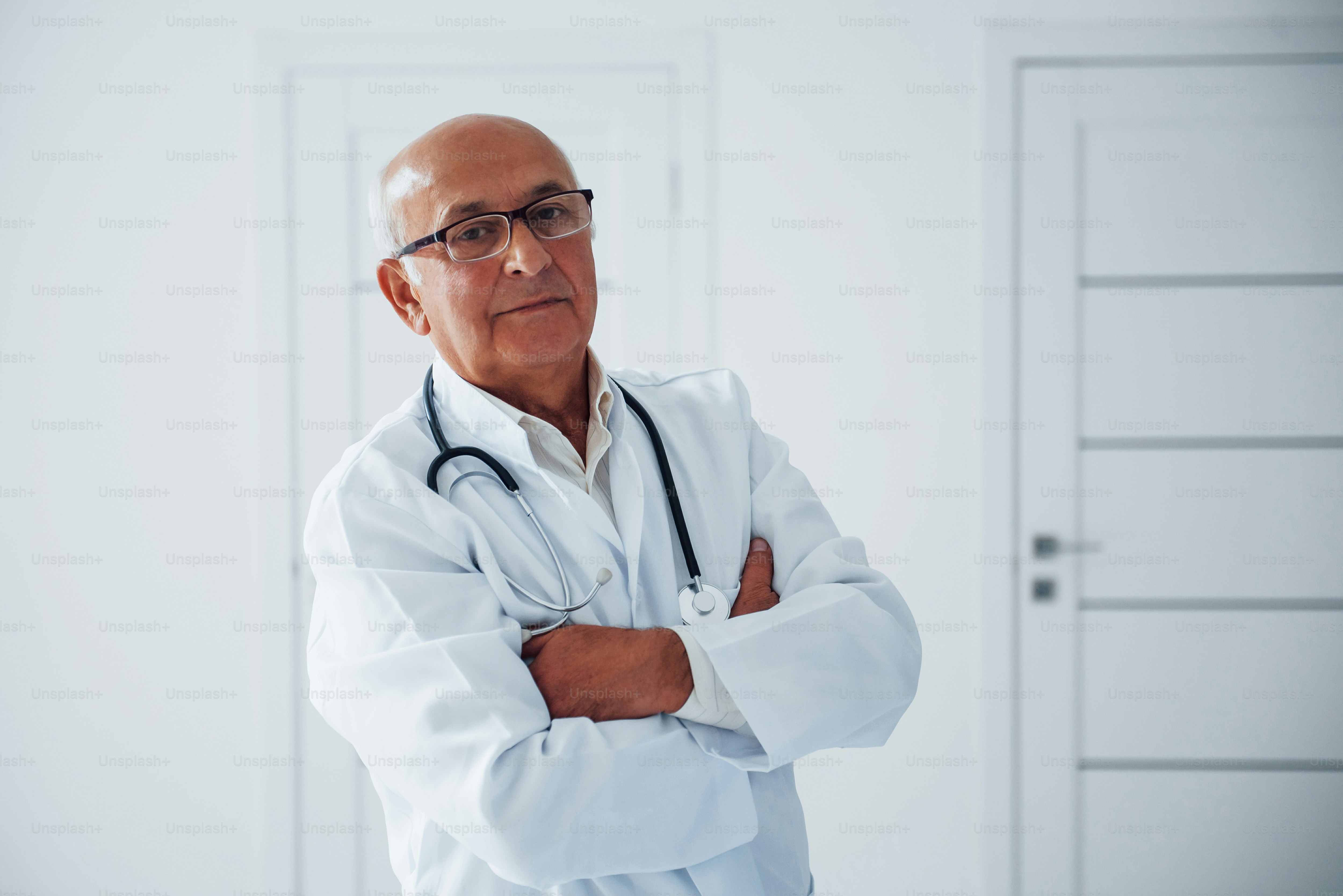 Portrait of senior doctor in white uniform that stands in the clinic.
