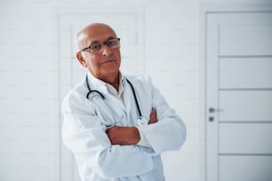 Retrato del médico mayor con uniforme blanco que se encuentra en la clínica.
