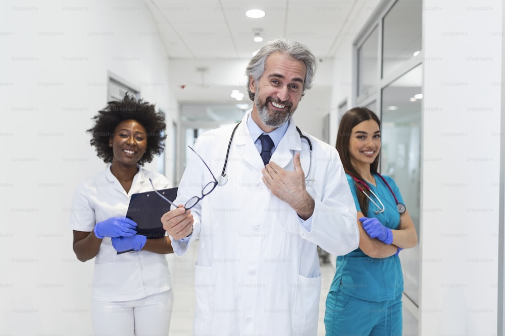 Concepto de clínica, profesión, gente, atención médica y medicina: grupo feliz de médicos o médicos en el corredor del hospital. Grupo de médicos en la sala del hospital - concepto de atención médica y medicina