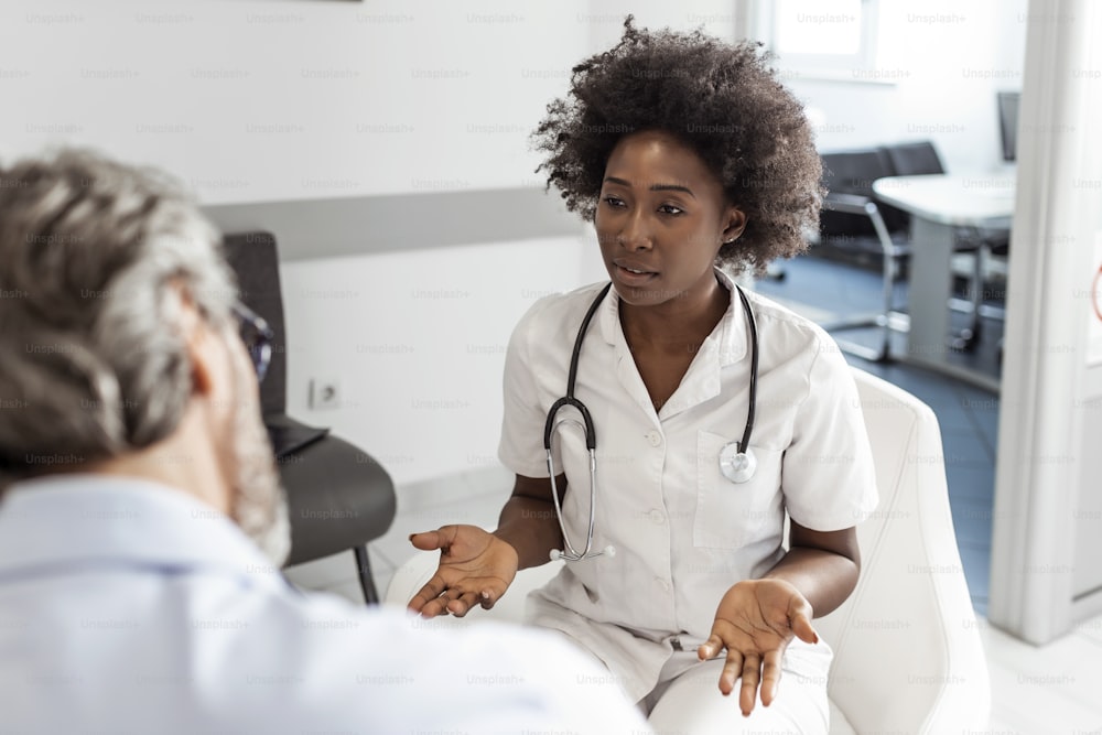 Schwarze Ärztin und älterer Mann kommunizieren in einem Wartezimmer im Krankenhaus. Medizin-, Gesundheits- und Menschenkonzept - Arzt- und Patiententreff im Krankenhaus