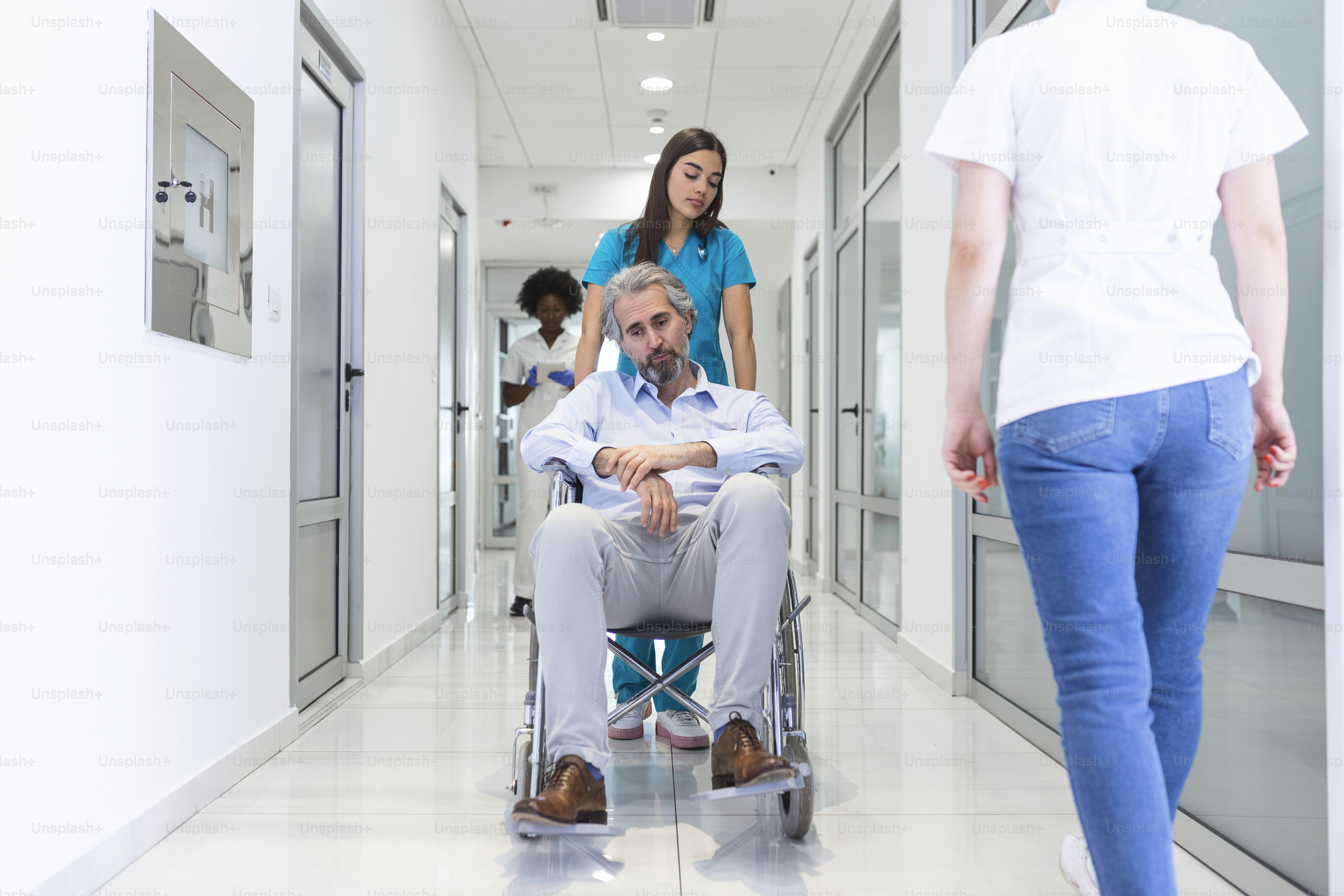 Wheelchair patient with professional female doctor and nurse specialist staff in corridor of hospital recovery center
