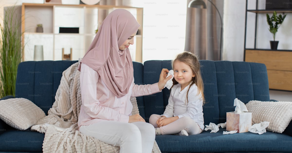 Front view of young pretty mother, Muslim woman in hijab, sitting on ...