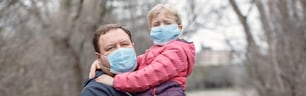 Father with child girl wearing sanitary face masks outdoor. Family dad and daughter protect themselves from dangerous spread of coronavirus covid-19. Banner header for website.