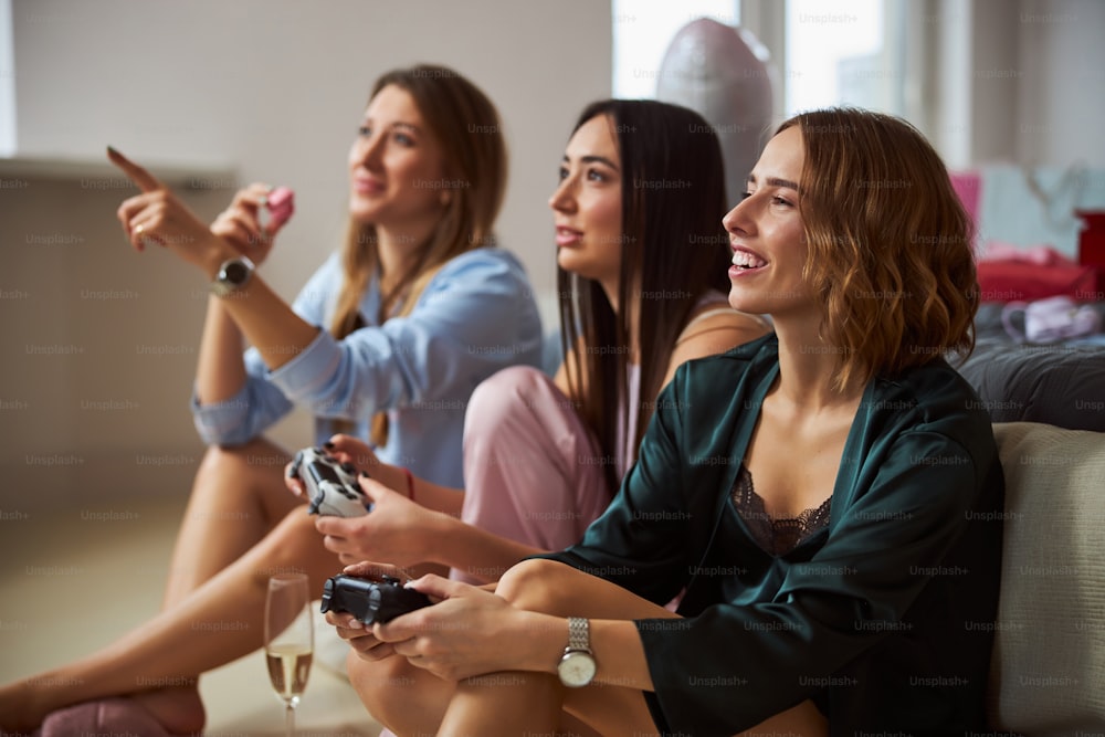 Donna con un macaron alla fragola seduta sul pavimento dai suoi amici che giocano a un videogioco