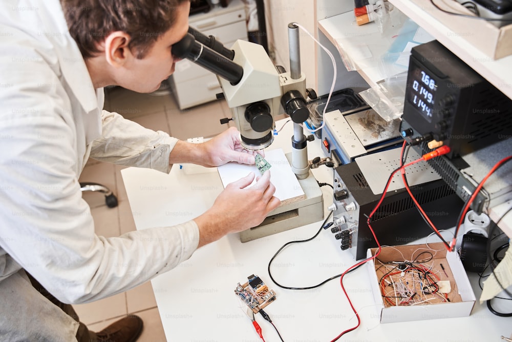 Engineer scientists looking at the microscope at the schema while developing bionical hand at the laboratory. Engineering of the bionic hands concept. Stock photo