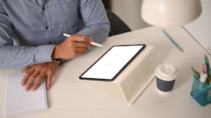 Cropped shot of businessman holding stylus pen writing on digital tablet at his office desk.