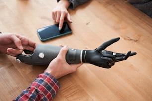 Look at this. Close up portrait of the male engineer showing a prosthesis of a hand to his female colleague. Woman touching bionic hand during testing. Stock photo