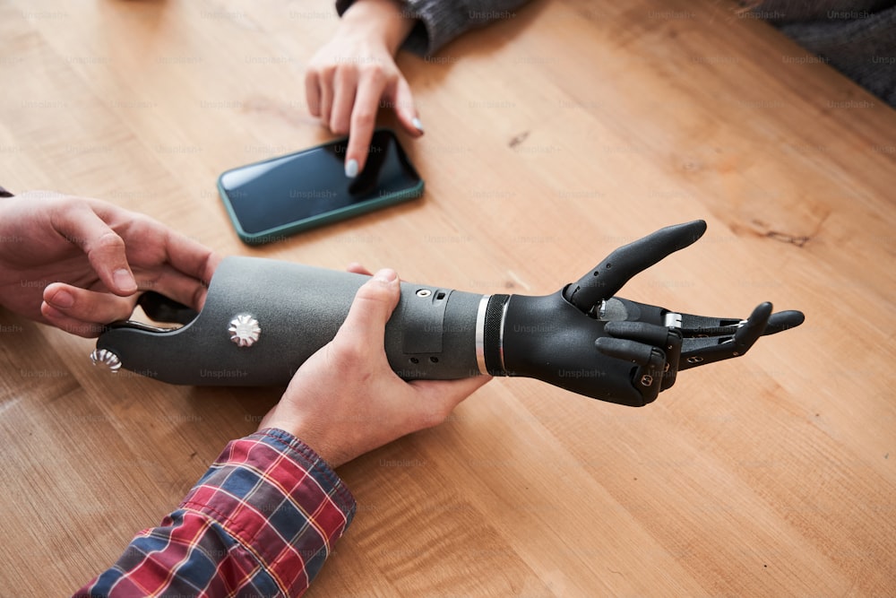 Look at this. Close up portrait of the male engineer showing a prosthesis of a hand to his female colleague. Woman touching bionic hand during testing. Stock photo