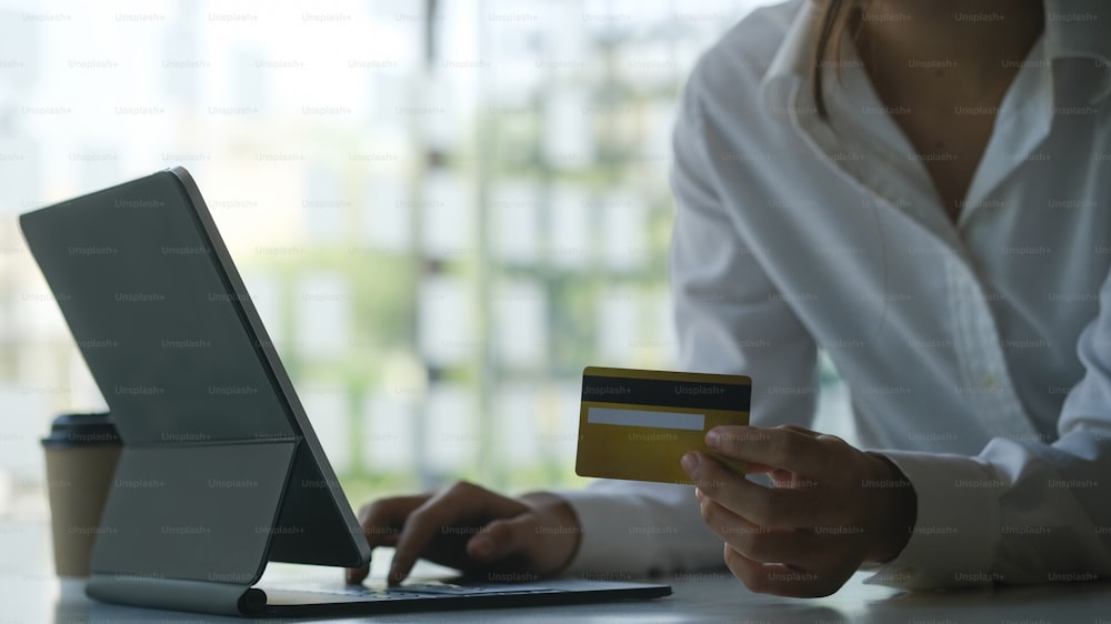 Cropped shot of young female holding credit card and shopping online or online payment with computer tablet.