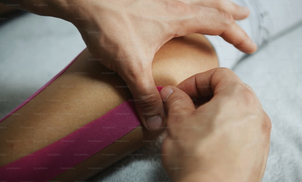 Doctor helps woman by leg treatment with kinesio tape.